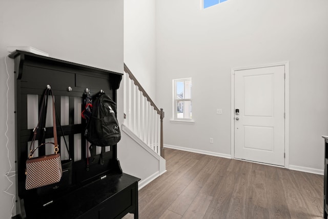 entrance foyer with wood finished floors, stairway, baseboards, and a high ceiling