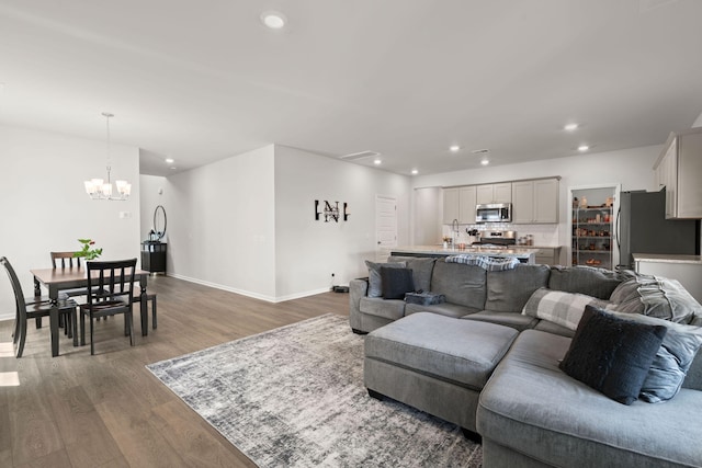 living area with wood finished floors, recessed lighting, a chandelier, and baseboards