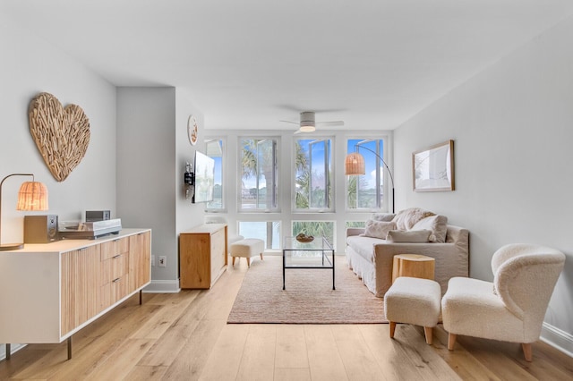 sitting room with light wood finished floors, a ceiling fan, and baseboards