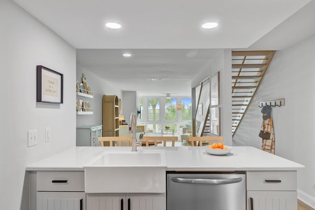 kitchen with stainless steel dishwasher, a sink, light countertops, and recessed lighting