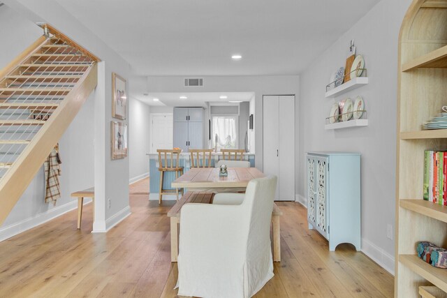 dining area featuring light wood-type flooring, recessed lighting, baseboards, and stairway