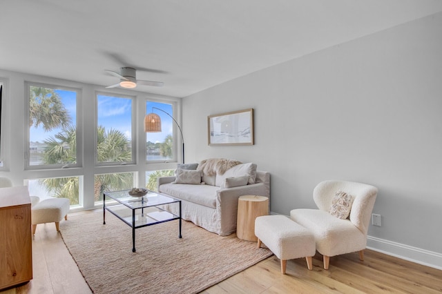 living area with light wood-type flooring, a ceiling fan, and baseboards