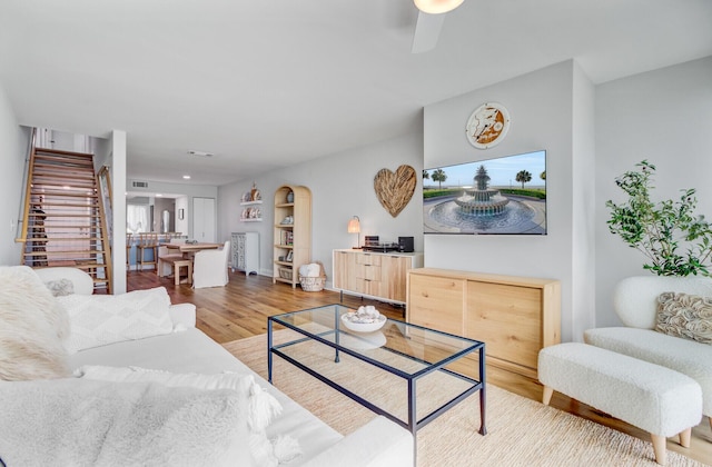 living room featuring stairway, wood finished floors, and a ceiling fan