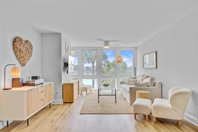 sitting room with light wood-style floors, a ceiling fan, and baseboards
