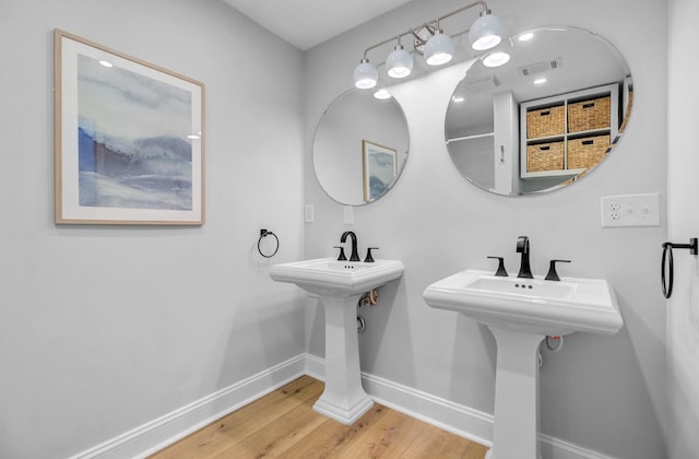 bathroom featuring baseboards, wood finished floors, and a sink