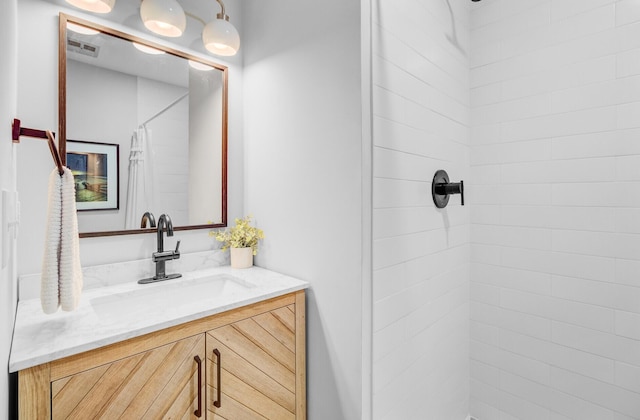 full bath featuring tiled shower and vanity