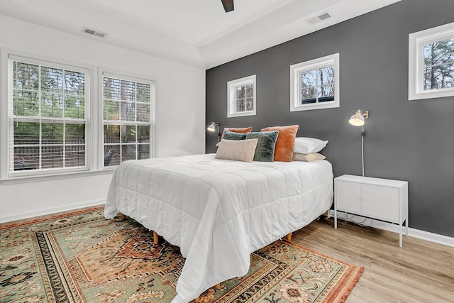 bedroom with baseboards, visible vents, ceiling fan, and wood finished floors