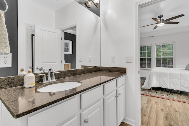 ensuite bathroom with ceiling fan, ensuite bath, wood finished floors, and vanity