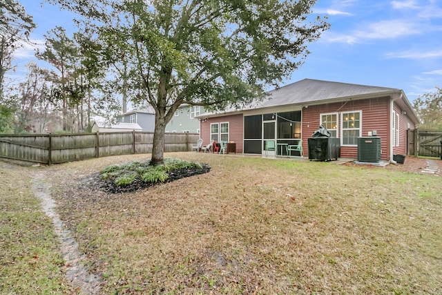 back of house with a yard, a fenced backyard, a sunroom, and central air condition unit