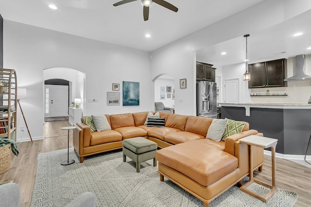 living room featuring arched walkways, recessed lighting, ceiling fan, light wood-type flooring, and baseboards