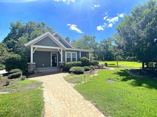 view of front of house featuring covered porch, a front lawn, board and batten siding, and a chimney