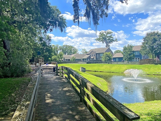 view of home's community with a lawn, a water view, fence, and a residential view