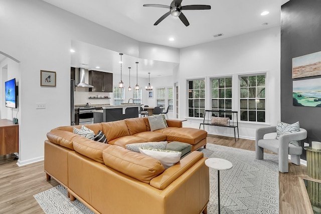 living room featuring visible vents, light wood-style flooring, and baseboards