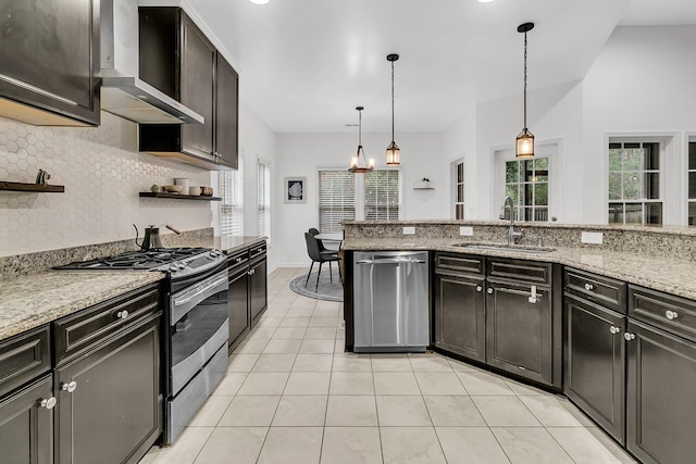 kitchen featuring wall chimney exhaust hood, appliances with stainless steel finishes, pendant lighting, open shelves, and a sink