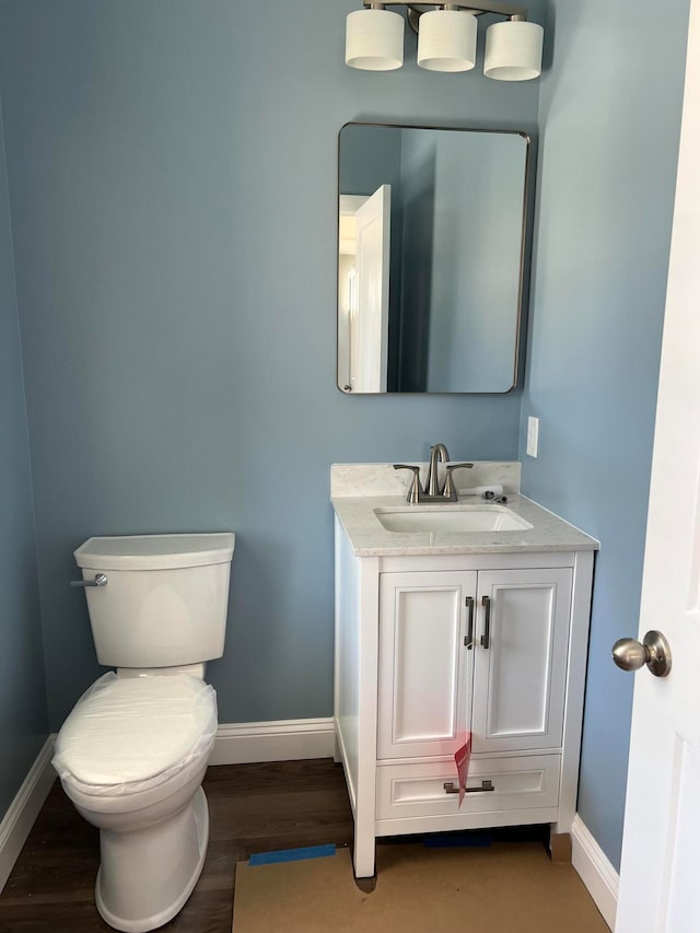 bathroom with toilet, vanity, and hardwood / wood-style floors