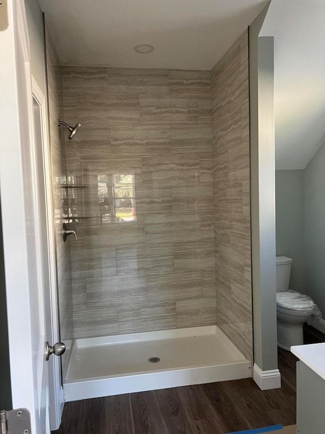 bathroom with toilet, vanity, hardwood / wood-style flooring, and tiled shower