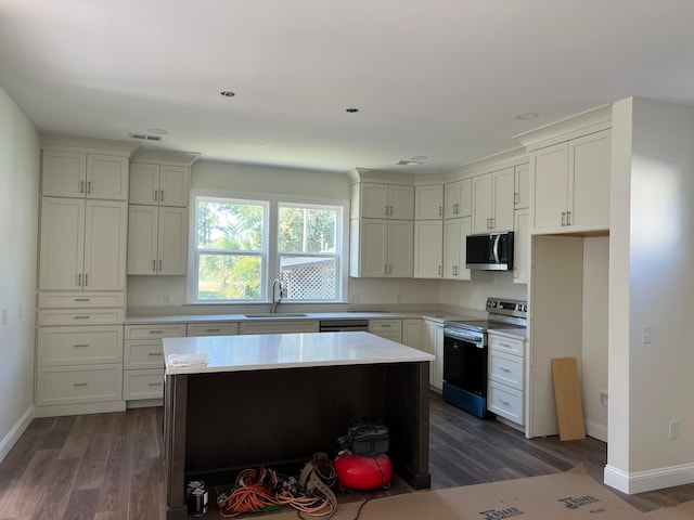 kitchen featuring white cabinetry, appliances with stainless steel finishes, dark hardwood / wood-style flooring, sink, and a center island