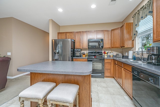 kitchen featuring a breakfast bar area, visible vents, a kitchen island, a sink, and black appliances