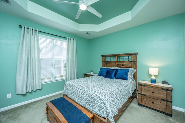 bedroom featuring a tray ceiling, baseboards, carpet floors, and visible vents