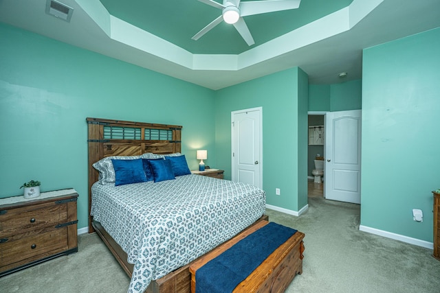 carpeted bedroom featuring a raised ceiling, baseboards, visible vents, and ceiling fan