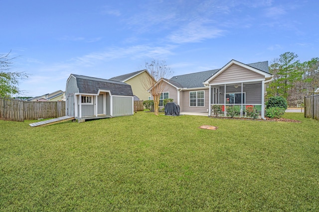 rear view of house featuring a yard, a storage unit, an outdoor structure, and a sunroom