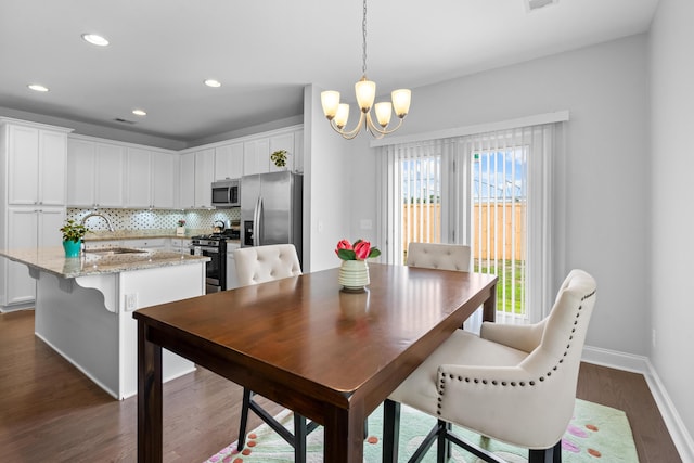 dining room with dark hardwood / wood-style flooring, an inviting chandelier, and sink