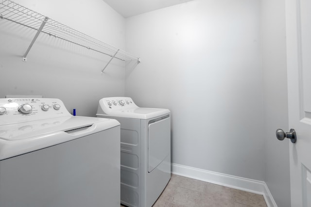 laundry area with light tile patterned floors and washing machine and clothes dryer