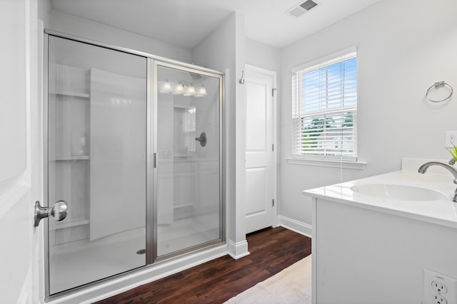 bathroom with wood-type flooring, a shower with door, and vanity