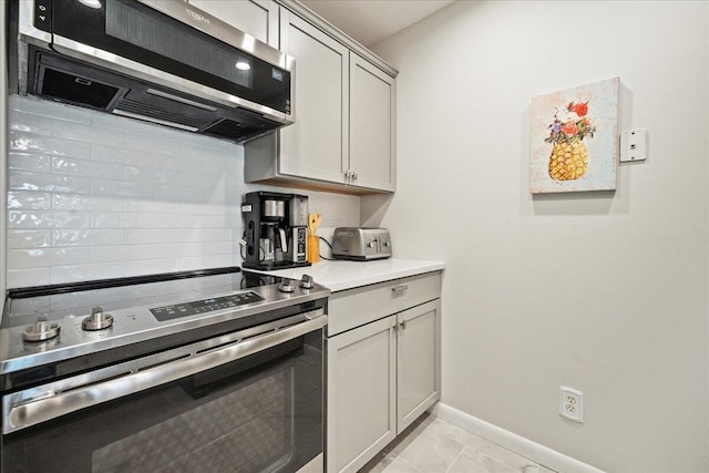 kitchen with light tile patterned floors, appliances with stainless steel finishes, and gray cabinetry