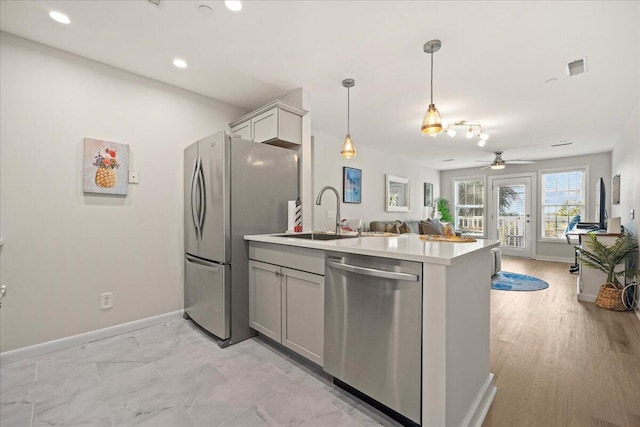 kitchen with pendant lighting, appliances with stainless steel finishes, sink, kitchen peninsula, and ceiling fan