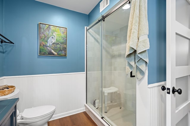 bathroom with hardwood / wood-style flooring, vanity, toilet, and walk in shower