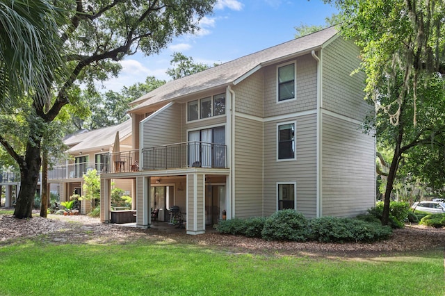 rear view of property with a balcony and a yard