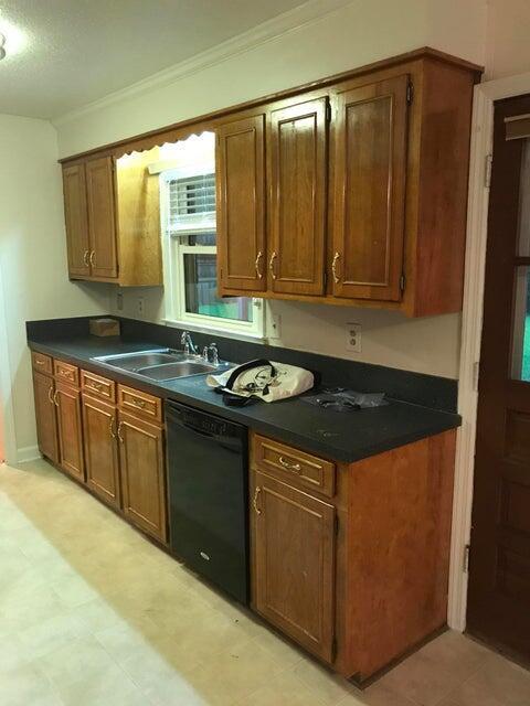 kitchen featuring dishwasher, a sink, dark countertops, ornamental molding, and brown cabinets