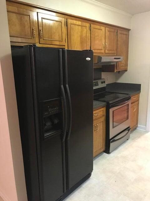 kitchen featuring black fridge, electric range, dark countertops, brown cabinetry, and ornamental molding