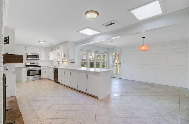kitchen with light countertops, light tile patterned floors, a sink, a peninsula, and appliances with stainless steel finishes