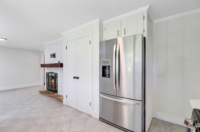 kitchen with a brick fireplace, crown molding, light tile patterned floors, and stainless steel fridge with ice dispenser