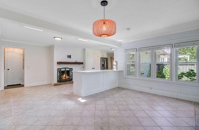 interior space featuring a peninsula, baseboards, a brick fireplace, stainless steel fridge with ice dispenser, and light countertops