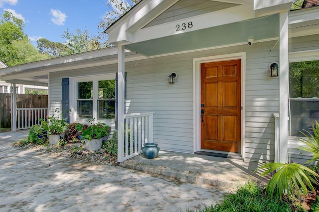 property entrance featuring a porch and fence