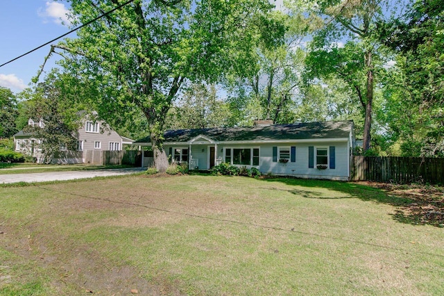 ranch-style home featuring a carport, a front yard, concrete driveway, and fence