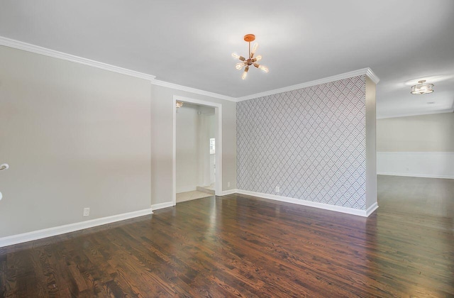 spare room with an accent wall, crown molding, wood finished floors, an inviting chandelier, and baseboards