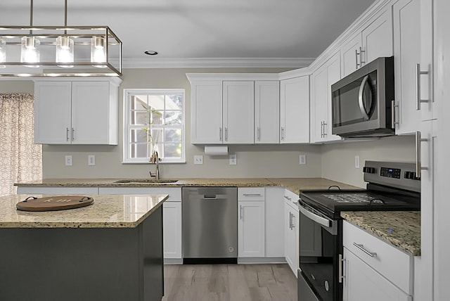 kitchen featuring light wood finished floors, stainless steel appliances, crown molding, white cabinetry, and a sink