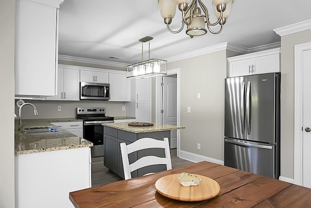 kitchen with white cabinets, light stone counters, appliances with stainless steel finishes, ornamental molding, and a sink