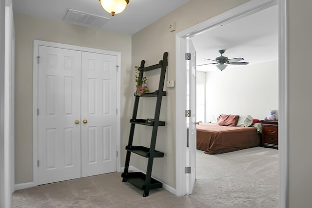 hallway with carpet floors, visible vents, and baseboards