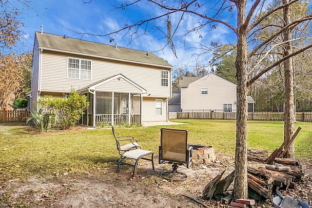 rear view of property featuring an outdoor fire pit, a lawn, a fenced backyard, and a sunroom