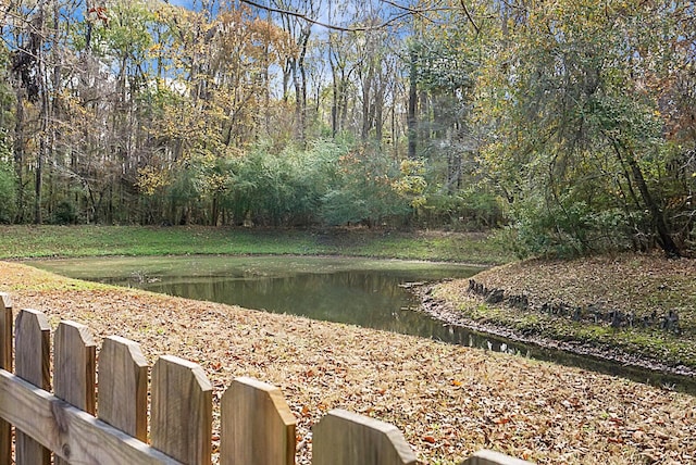 property view of water featuring fence and a wooded view