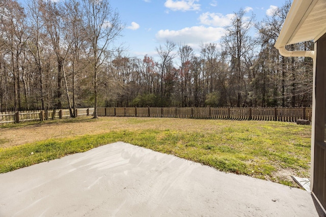 view of yard featuring a patio area, a fenced backyard, and a view of trees