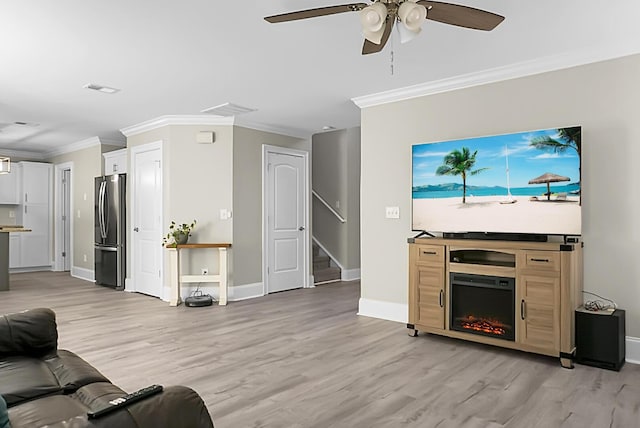 living area featuring light wood-type flooring, stairs, and crown molding