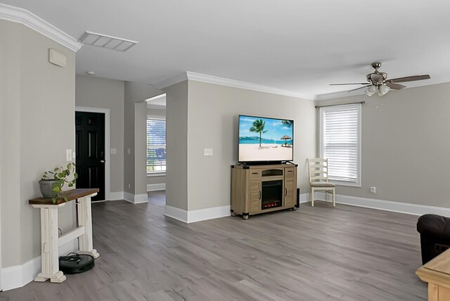 living area featuring ornamental molding, plenty of natural light, wood finished floors, and visible vents