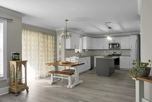 kitchen featuring ornamental molding, appliances with stainless steel finishes, a kitchen island, and visible vents