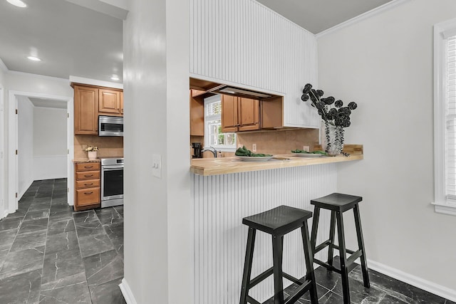 kitchen with crown molding, marble finish floor, stainless steel microwave, and backsplash